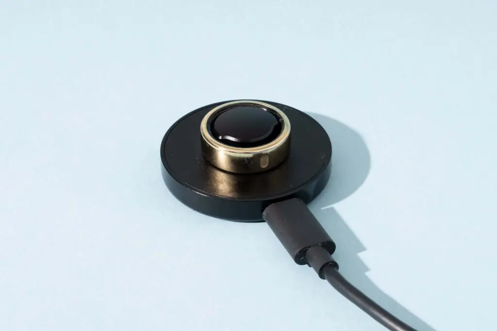 Close-up of Oura Ring Gen 3 on charger, showcasing compact design and charging indicator light.