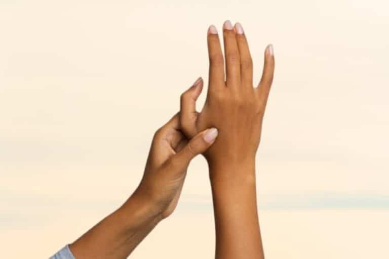 Woman applying acupressure to hand to relieve chronic pain naturally