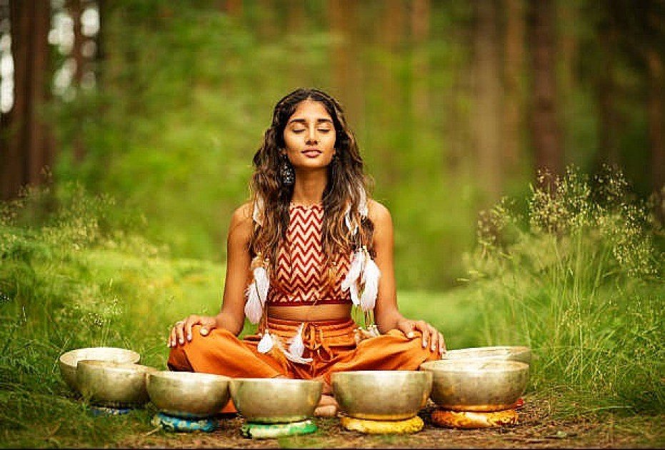 Woman meditating with Ayurvedic herbs and sunlight symbolizing mind-body balance