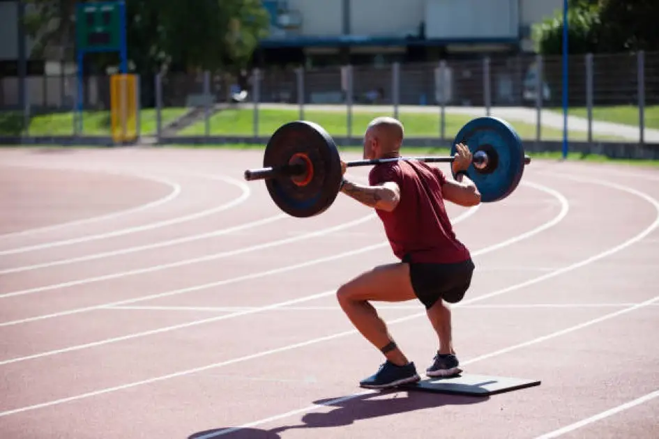 Person lifting weights with a running track background, symbolizing the fusion of cardio and strength training.