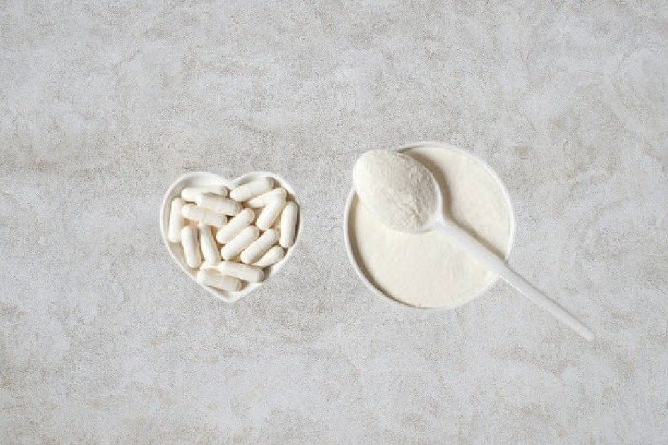 Collagen supplement capsules spilling from a glass jar on a neutral background