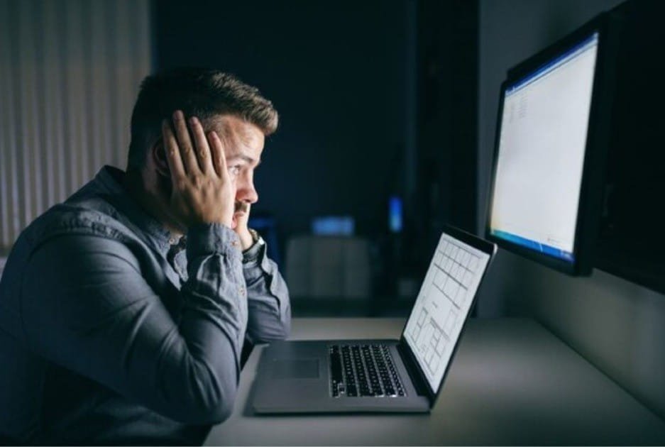 Person overwhelmed by screens, symbolizing the mental toll of unhealthy digital habits