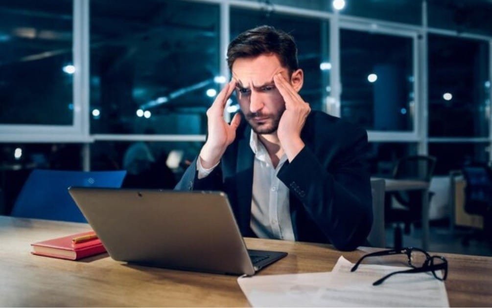Overwhelmed person surrounded by digital devices, symbolizing the stress of multitasking.
