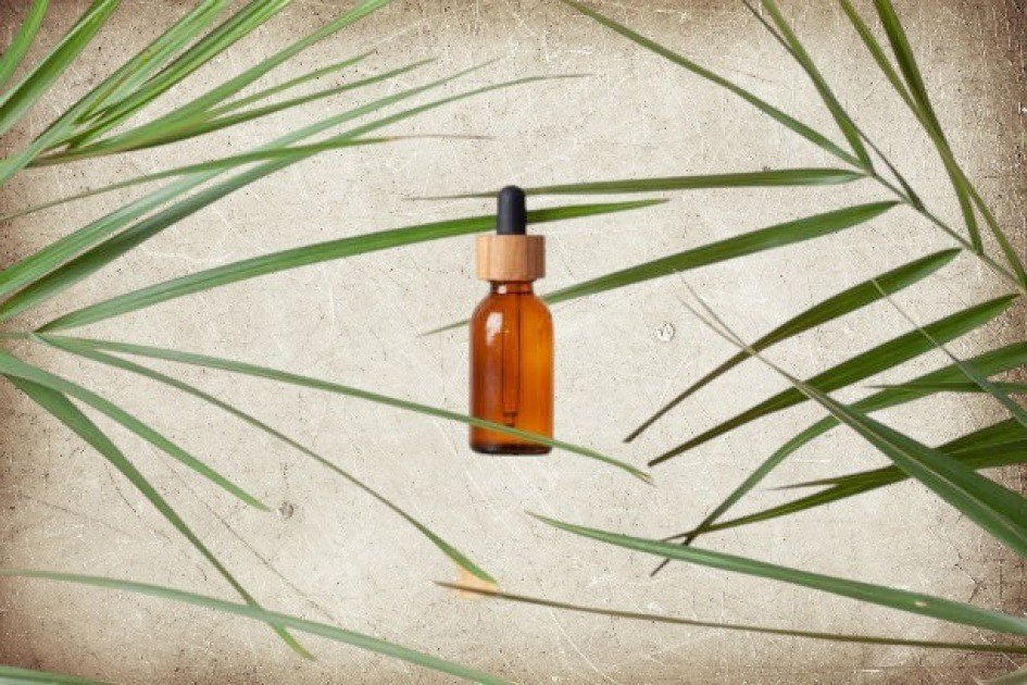 Amber glass bottle of eucalyptus essential oil with fresh eucalyptus leaves on a wooden surface