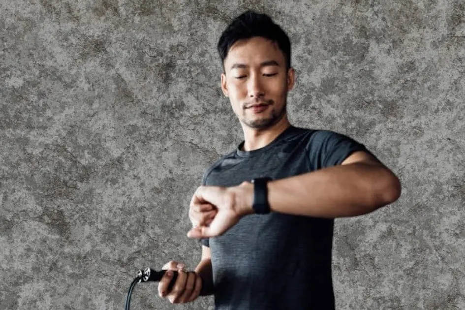 Person holding a clock and a fitness tracker, symbolizing the urgency to act on health goals and overcome procrastination.