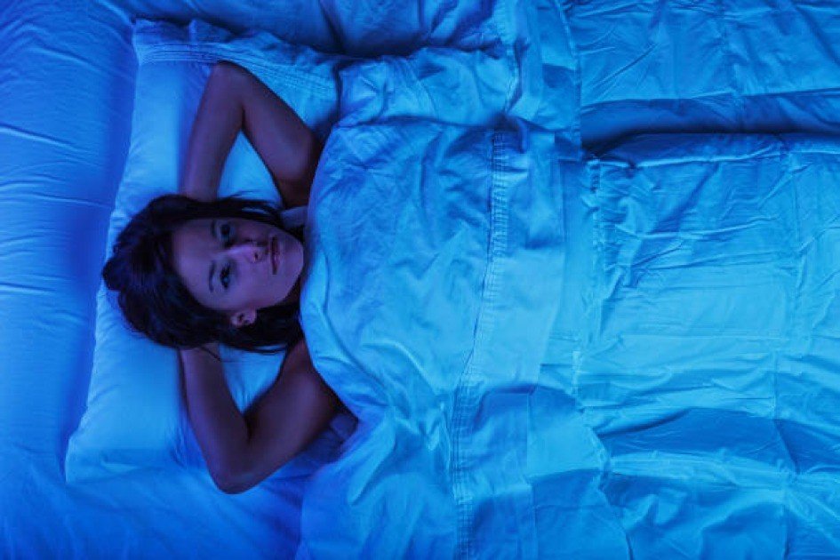 Person lying awake at night, battling insomnia under a dark, starry sky