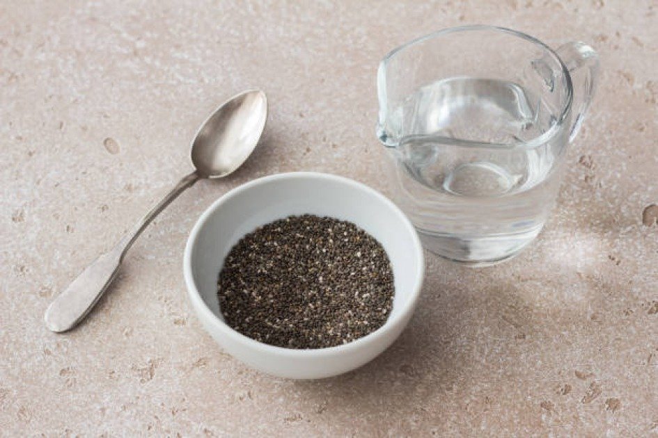 Chia seeds in a jar next to a cup of water, representing health benefits of intermittent fasting.