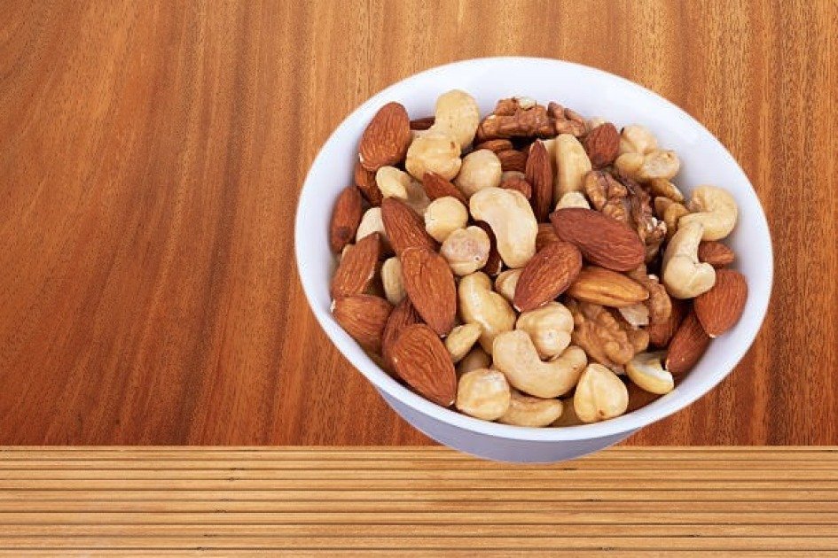 A bowl of assorted nuts and seeds on a rustic wooden table, symbolizing a healthy intermittent fasting snack.