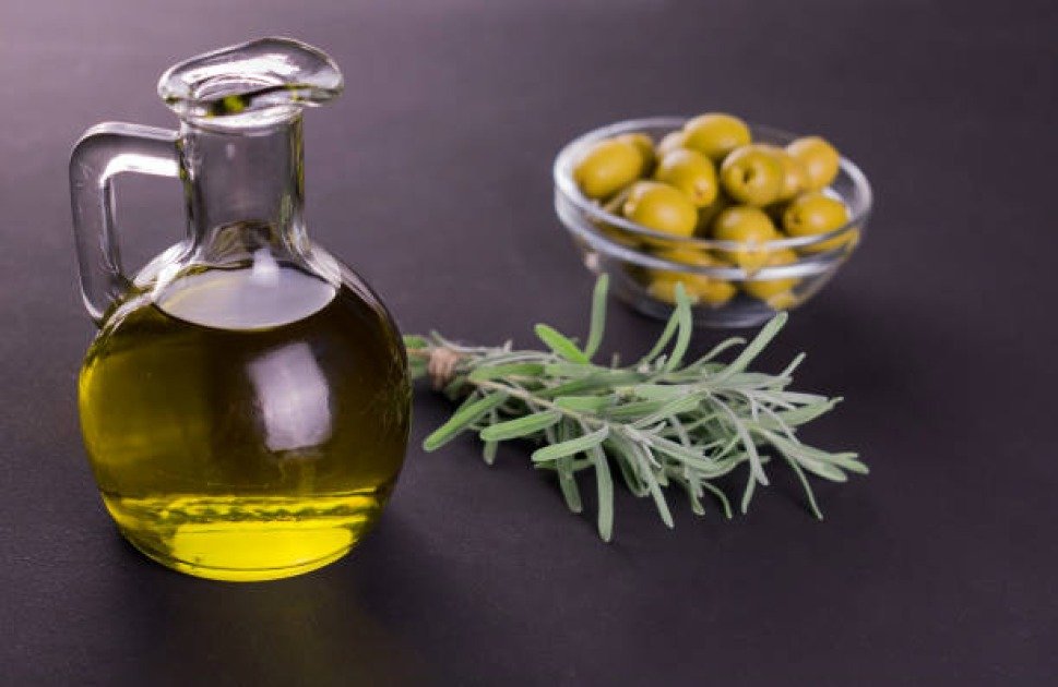 A glass bottle of olive oil on a wooden table, symbolizing clean fat for intermittent fasting.