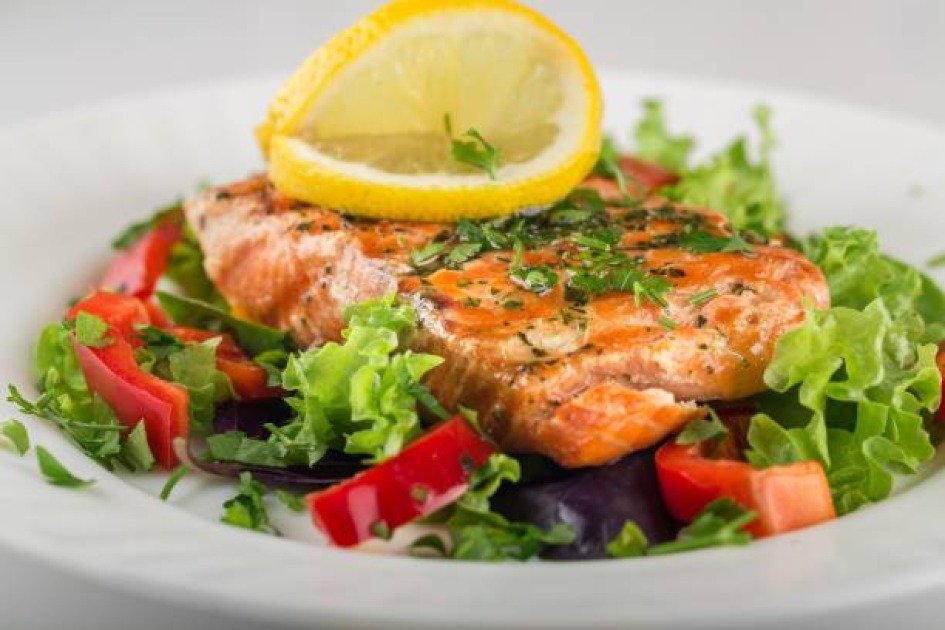 Grilled salmon fillet served with greens and lemon, symbolizing a healthy intermittent fasting meal.