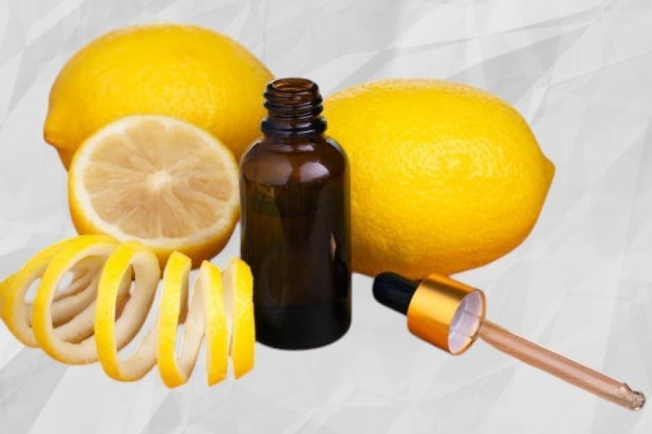 Fresh lemon slices and a bottle of lemon essential oil on a wooden table, glowing in natural light.