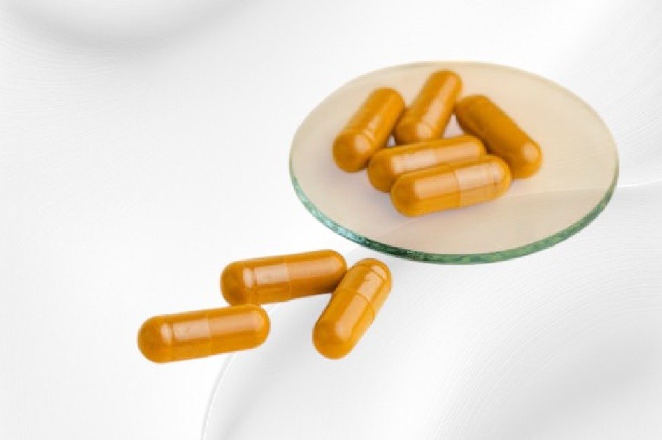 Close-up of magnesium supplement pills in a glass jar on a neutral background.