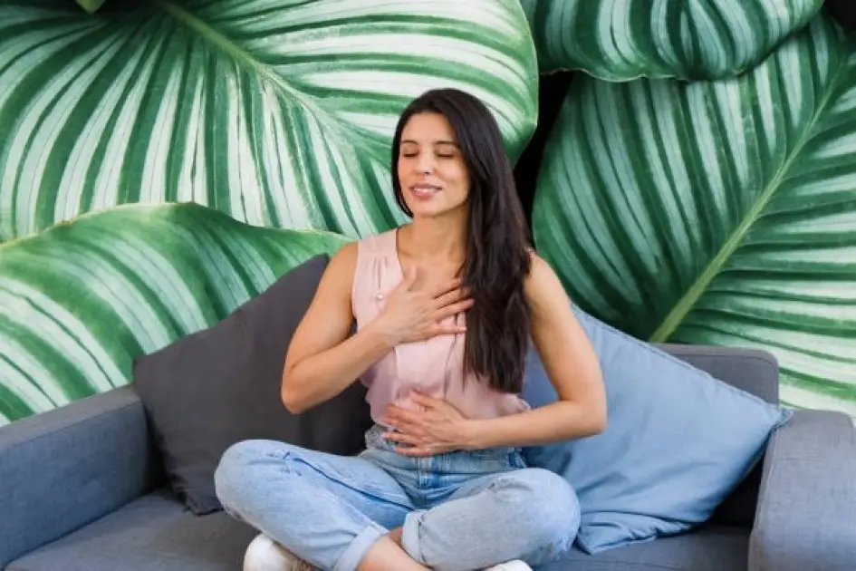 A person in serene meditation, exhaling deeply with eyes closed, bathed in soft natural light.