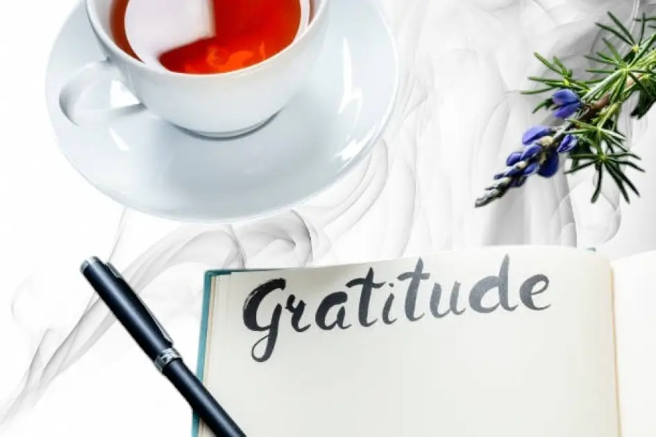 Open journal on a cozy table with a cup of tea and a handwritten gratitude list.