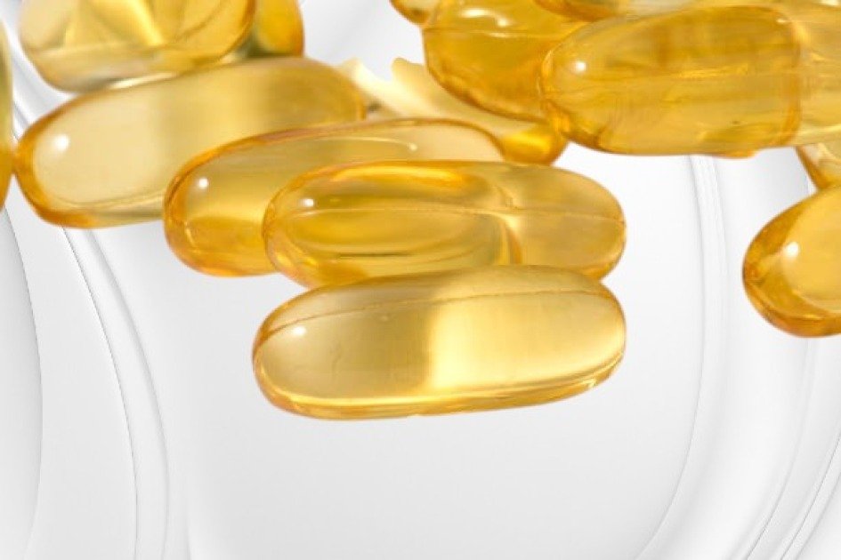 oftgel omega-3 capsules spilling from a bottle onto a clean white surface, highlighting their golden hue and purity.