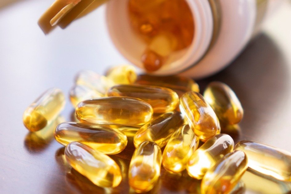 Golden Omega-3 fish oil capsules spilling from a daily supplement bottle