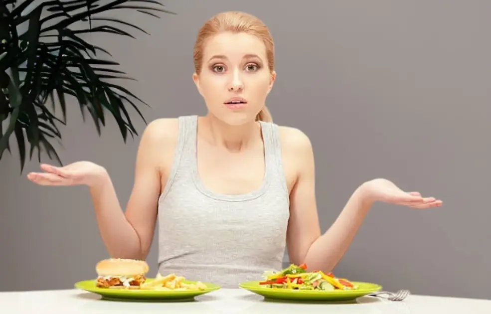 Frustrated person surrounded by paleo foods, with unhealthy elements subtly hidden in the background.