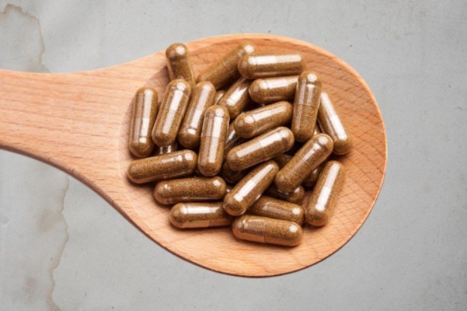 Close-up of probiotic capsules on a wooden spoon, symbolizing gut health and wellness.