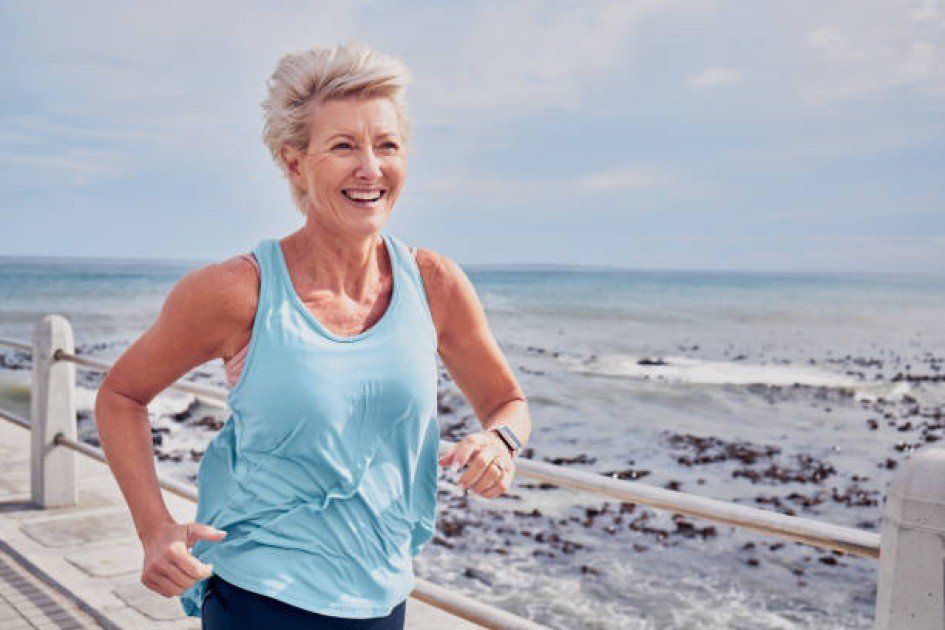 Active senior woman smiling while doing a low-impact cardio workout outdoors, promoting healthy aging.