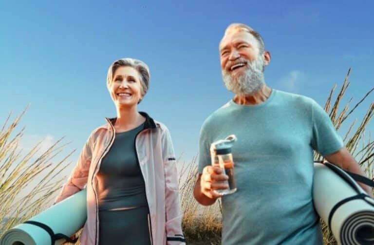 Active senior man and woman smiling during an outdoor fitness session, symbolizing vitality and healthy aging.
