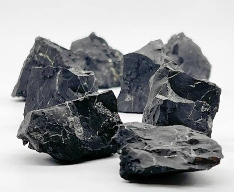 Polished black Shungite crystal resting on a reflective surface, glowing with subtle energy.