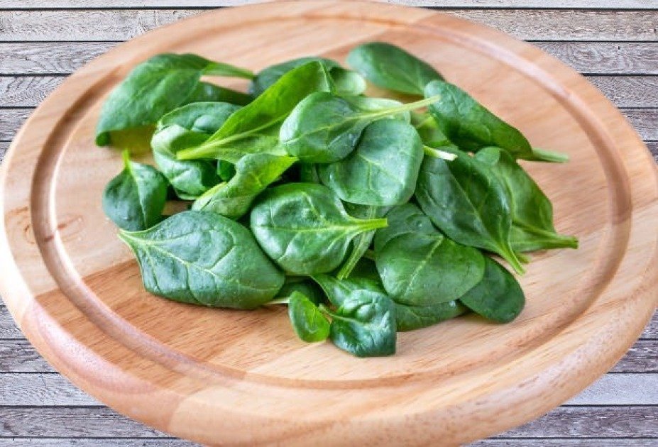 Fresh spinach leaves on a wooden board, highlighting their role as a powerful immune-boosting superfood.