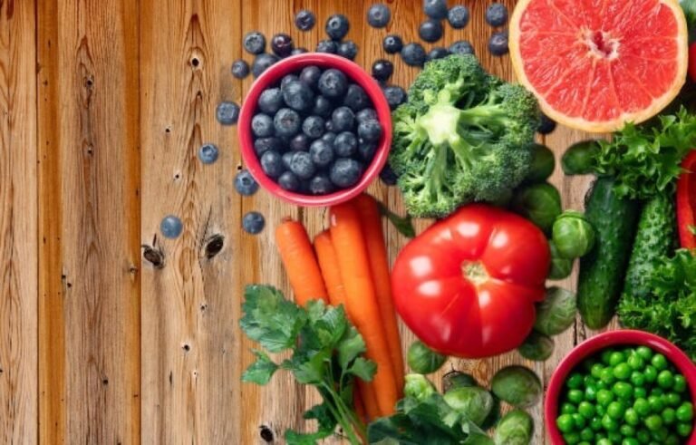Colorful assortment of superfoods including berries, leafy greens, nuts, and seeds on a rustic wooden table.
