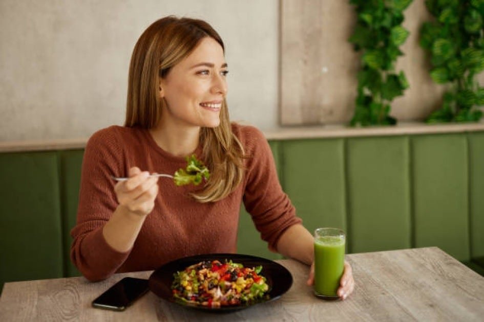 Smiling woman enjoying a colorful vegetarian meal, symbolizing emotional well-being through diet