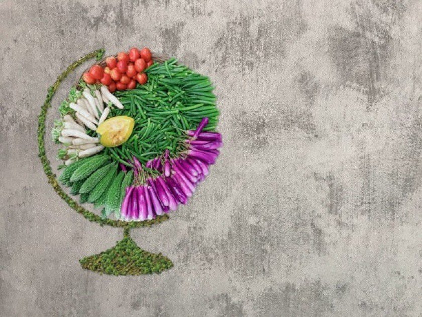 Colorful assortment of fresh vegetables arranged in the shape of Earth, symbolizing sustainable eating.