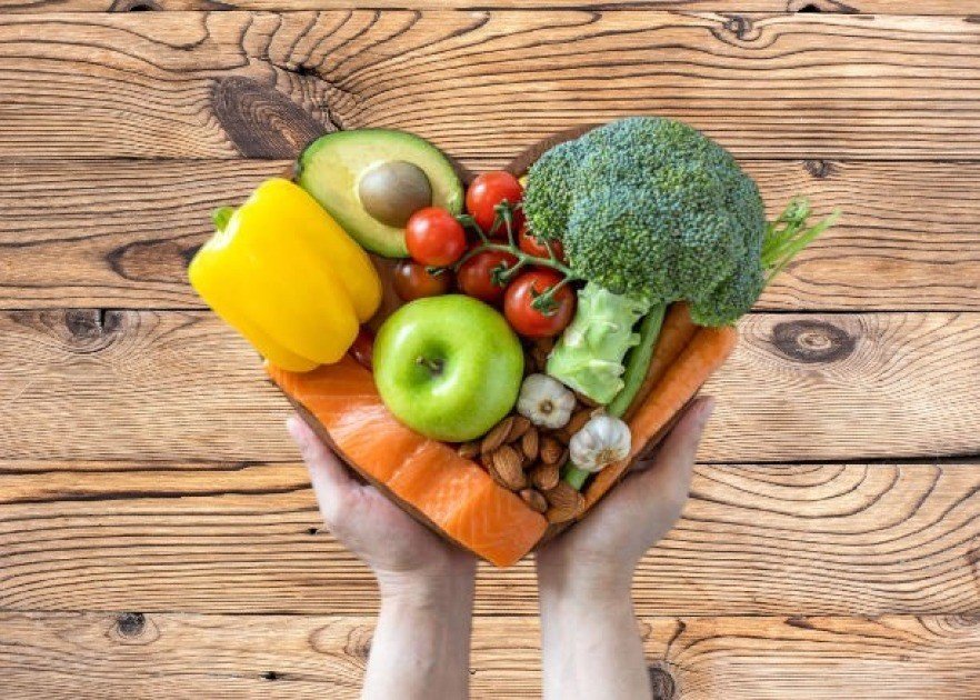 A heart-shaped bowl filled with fresh vegetables and legumes, symbolizing heart health through a vegetarian diet.