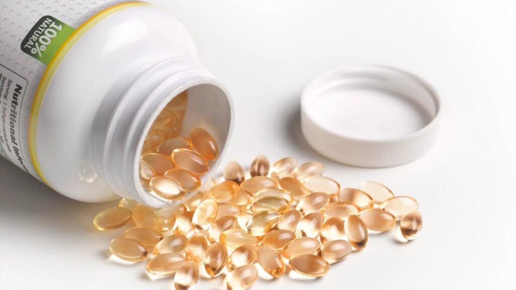 A bottle of Vitamin D supplements spilling softgel capsules onto a white surface under warm sunlight