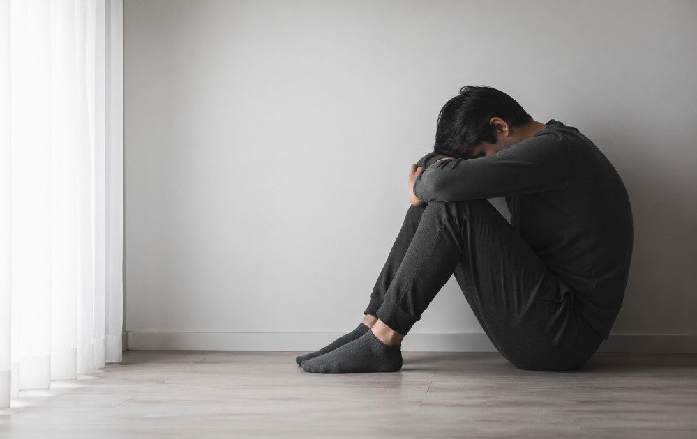 Person sitting alone, showing low energy and withdrawn mood, representing depression with loss of drive, interest, and energy.