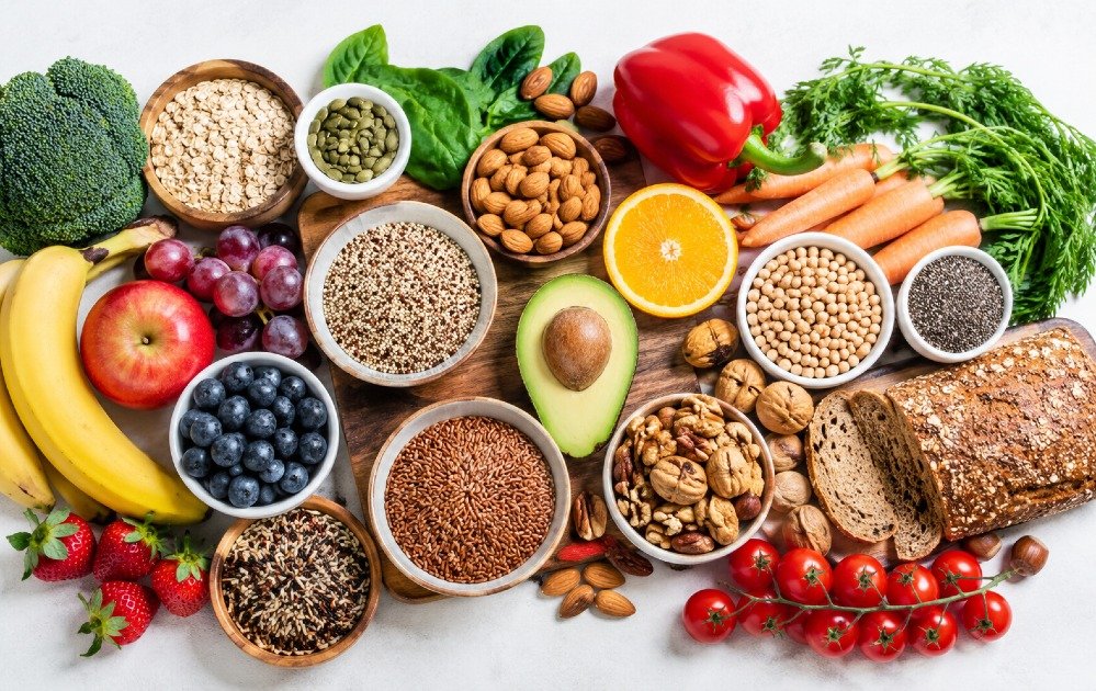 Fresh whole foods selection including fruits, vegetables, grains, and nuts arranged to promote a healthier daily diet.
