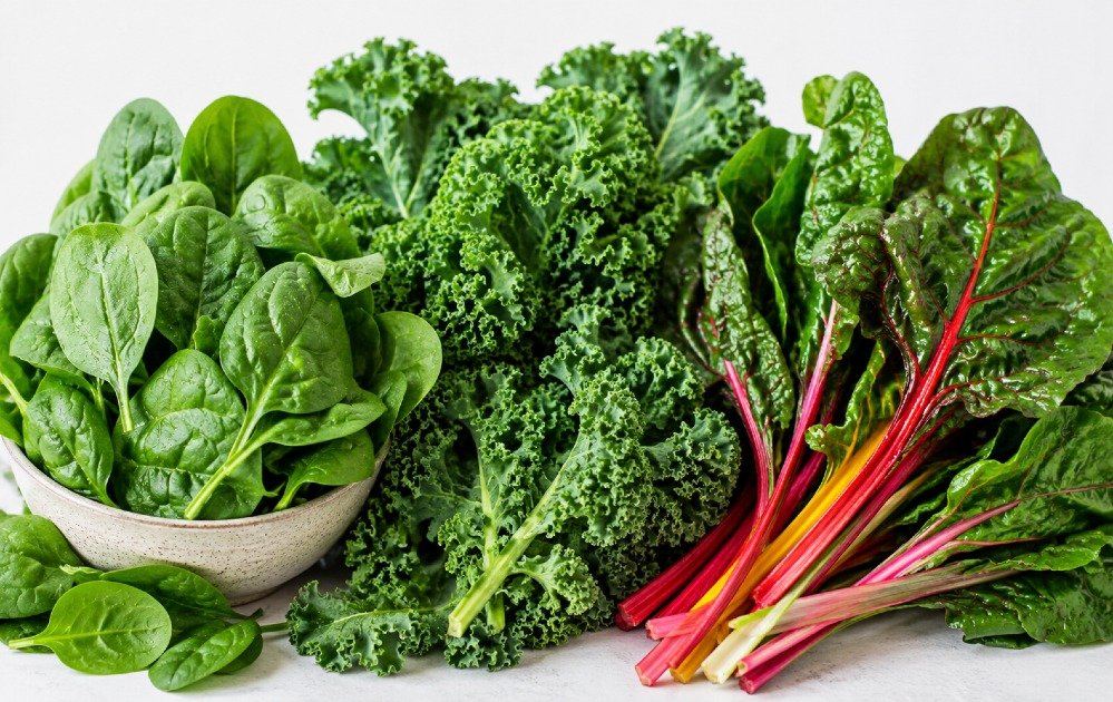 Fresh leafy green vegetables including spinach, kale, and chard arranged for healthy eating and nutrition.