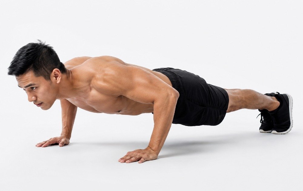 Person performing push-ups to strengthen chest, shoulders, triceps, and core muscles