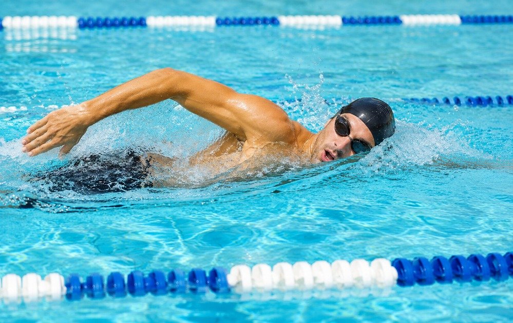 Person swimming freestyle in a pool, demonstrating full-body low-impact cardio exercise for fitness and endurance.